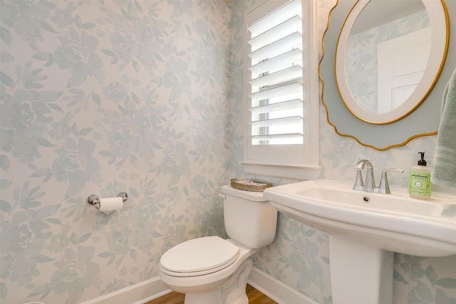 bathroom featuring baseboards, toilet, and wallpapered walls