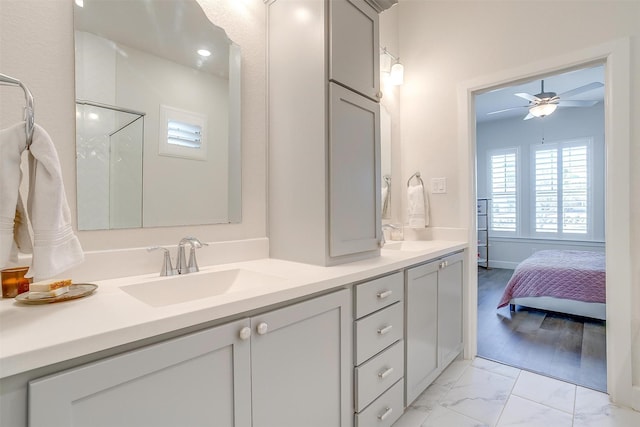 full bath with double vanity, marble finish floor, ceiling fan, and a sink