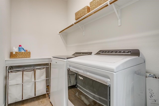 laundry room with laundry area, wood finished floors, and washing machine and dryer