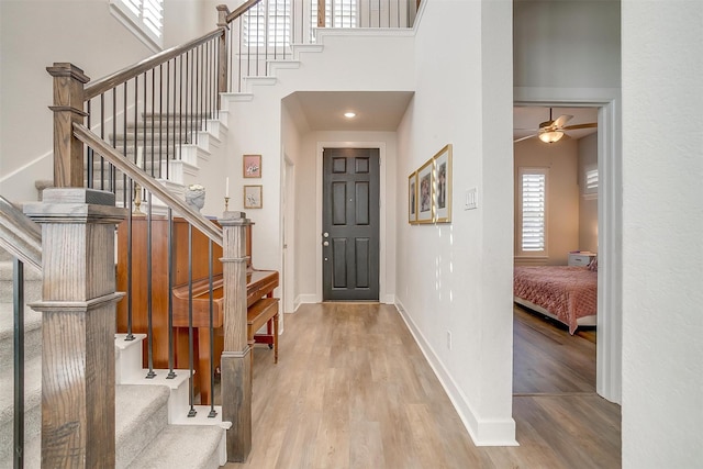 entryway featuring a towering ceiling, stairs, baseboards, and wood finished floors