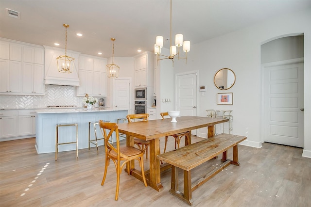 dining space with arched walkways, light wood-type flooring, visible vents, and recessed lighting