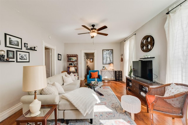 living area with ceiling fan, baseboards, and wood finished floors