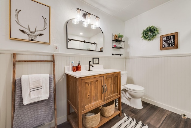 bathroom with a shower, wainscoting, toilet, wood finished floors, and vanity