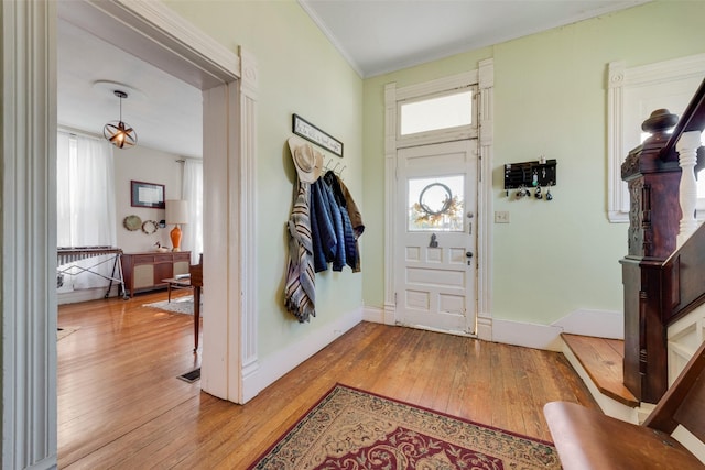 entryway with light wood finished floors, baseboards, and crown molding