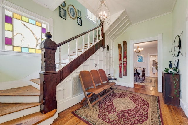 staircase with arched walkways, a notable chandelier, wood finished floors, baseboards, and crown molding