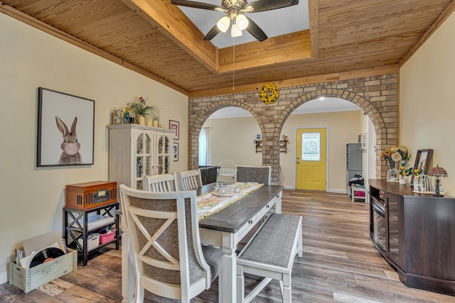 dining room with wood ceiling, arched walkways, a raised ceiling, and wood finished floors