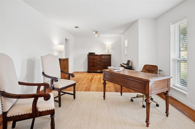 home office featuring light wood finished floors, plenty of natural light, and baseboards