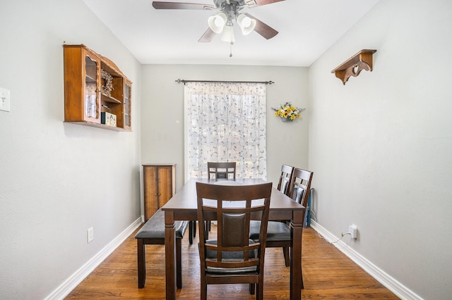 dining area with a ceiling fan, baseboards, and wood finished floors