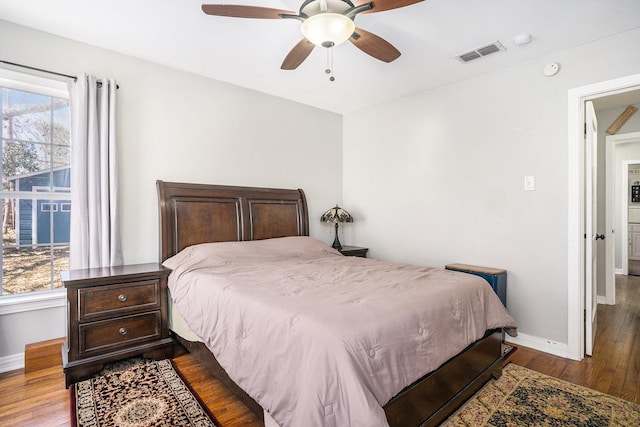 bedroom with a ceiling fan, visible vents, dark wood finished floors, and baseboards