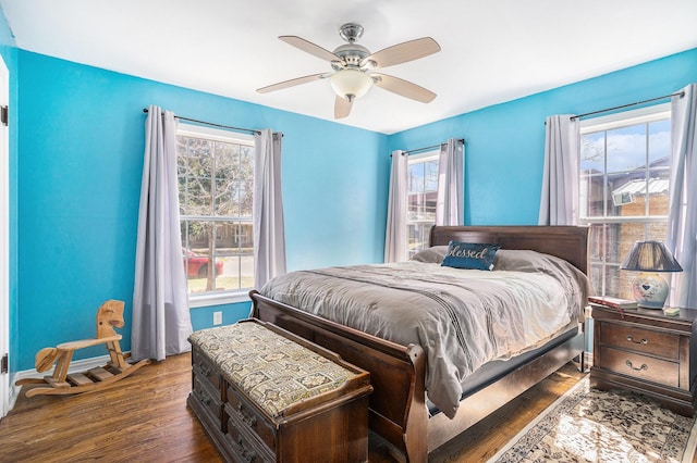 bedroom with ceiling fan, wood finished floors, and baseboards