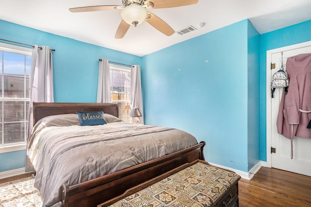 bedroom with a ceiling fan, baseboards, visible vents, and wood finished floors