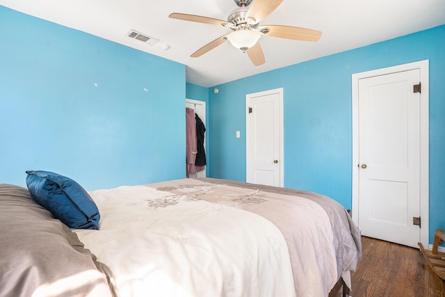 bedroom featuring a ceiling fan, visible vents, and wood finished floors