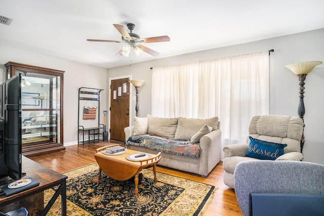 living room featuring visible vents, wood finished floors, a ceiling fan, and baseboards