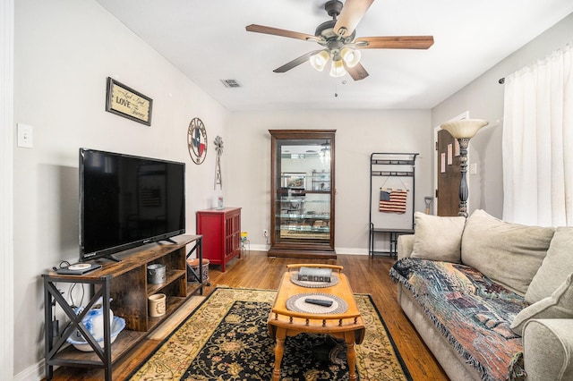 living room featuring a ceiling fan, baseboards, visible vents, and wood finished floors