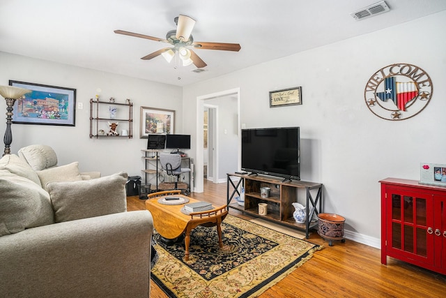 living area featuring a ceiling fan, baseboards, visible vents, and wood finished floors