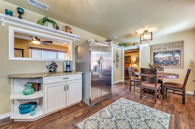 kitchen with dark wood-style floors, white cabinets, stainless steel fridge, and visible vents