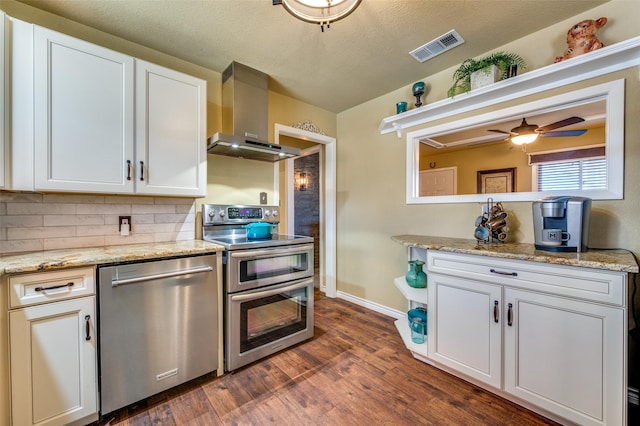 107 S Graves St, Mckinney, TX 75069 - kitchen featuring stainless steel appliances, wall chimney range hood, dark wood-style flooring, backsplash, and white cabinets