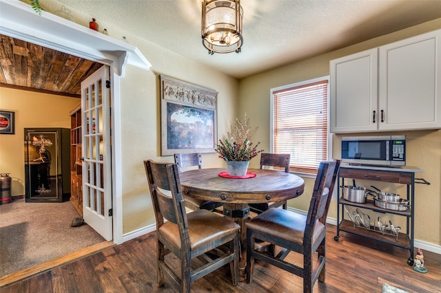 dining space featuring dark wood-style floors, a textured ceiling, and baseboards