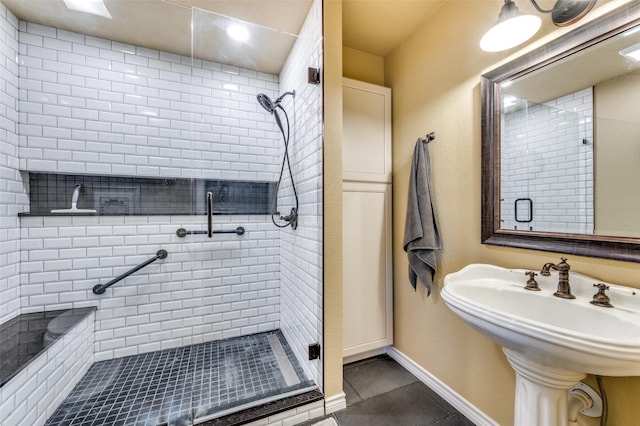 bathroom with a sink, a stall shower, tile patterned flooring, and baseboards