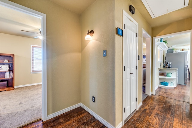 corridor featuring attic access, baseboards, and wood finished floors