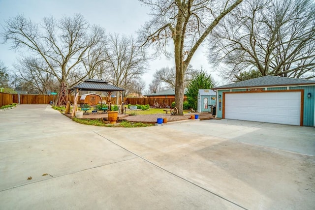 exterior space featuring a garage, an outbuilding, fence, and a gazebo