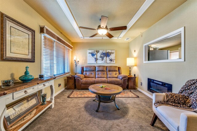 107 S Graves St, Mckinney, TX 75069 - carpeted living room with a ceiling fan, a raised ceiling, a textured ceiling, baseboards, and a glass covered fireplace
