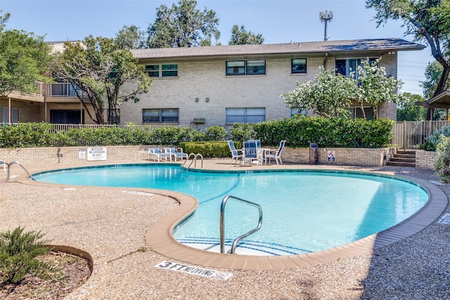 community pool featuring fence and a patio