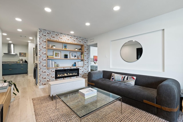 living room featuring light wood-style floors, recessed lighting, and a glass covered fireplace