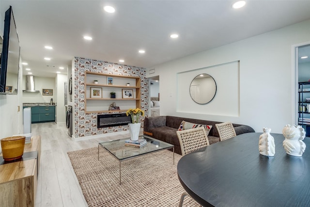 living room featuring light wood-style flooring, a glass covered fireplace, and recessed lighting