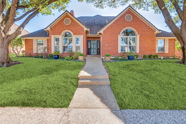 view of front of property with a front yard, brick siding, and a chimney