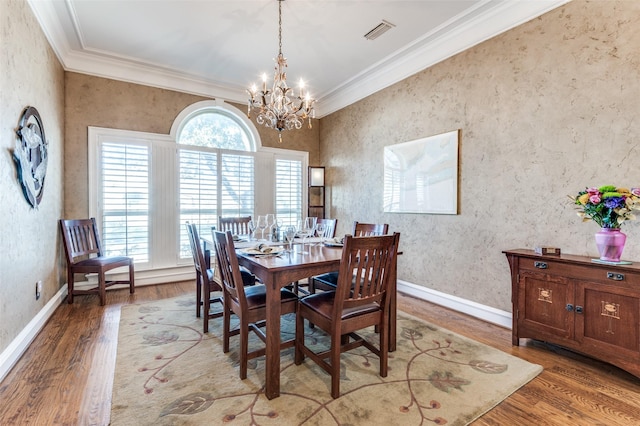 dining room with ornamental molding, visible vents, baseboards, and wood finished floors