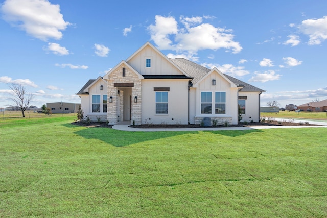 modern farmhouse with board and batten siding, a front yard, stone siding, and a shingled roof