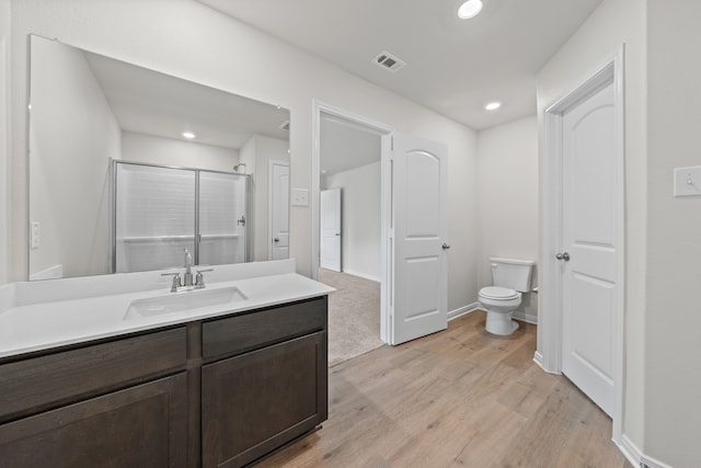 bathroom featuring toilet, recessed lighting, wood finished floors, vanity, and a shower stall