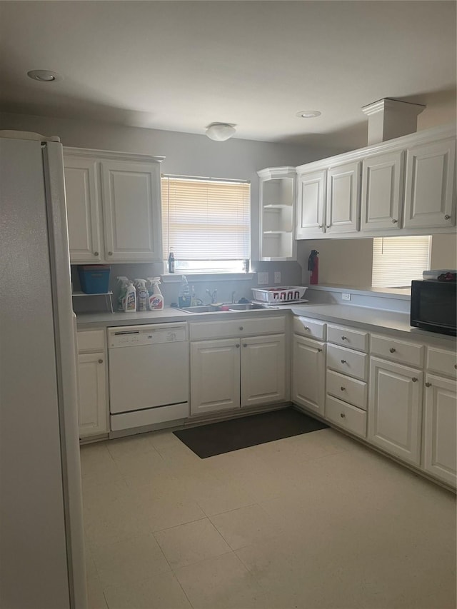 kitchen with a sink, white appliances, light countertops, and white cabinetry