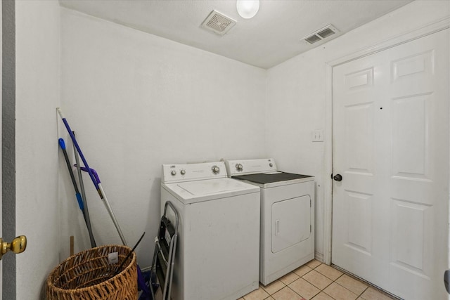 clothes washing area featuring visible vents, washing machine and clothes dryer, light tile patterned floors, and laundry area