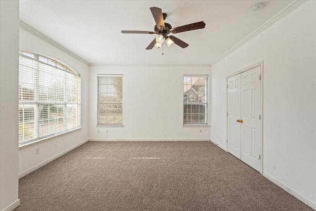 carpeted empty room with a wealth of natural light, crown molding, and baseboards