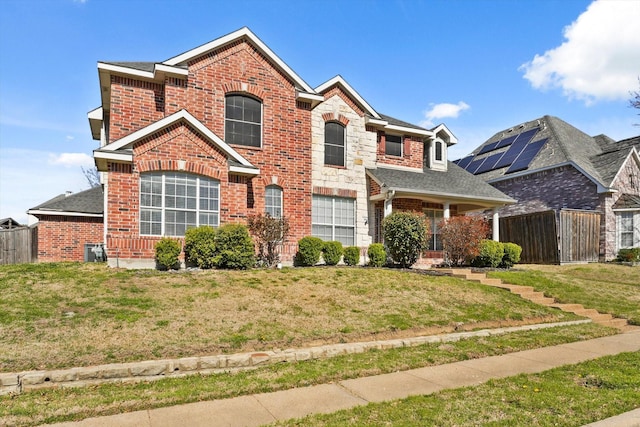 traditional-style house featuring a front yard, fence, brick siding, and roof with shingles