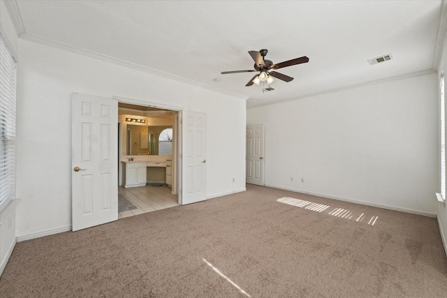 unfurnished bedroom featuring crown molding, connected bathroom, carpet floors, baseboards, and visible vents