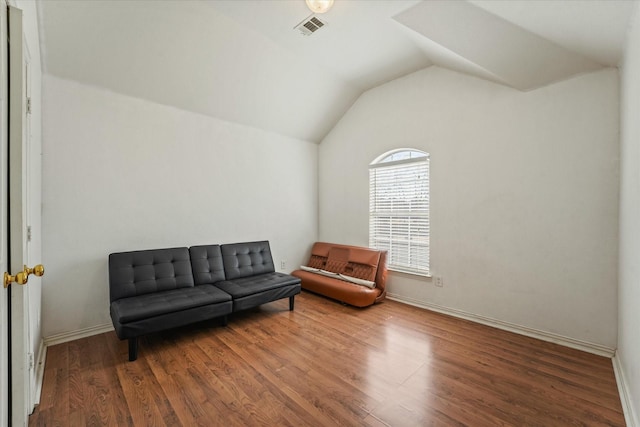 living area featuring vaulted ceiling, visible vents, baseboards, and wood finished floors