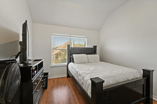 bedroom with vaulted ceiling, wood finished floors, and baseboards