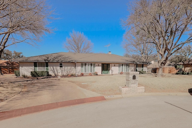 single story home with brick siding, a chimney, and fence