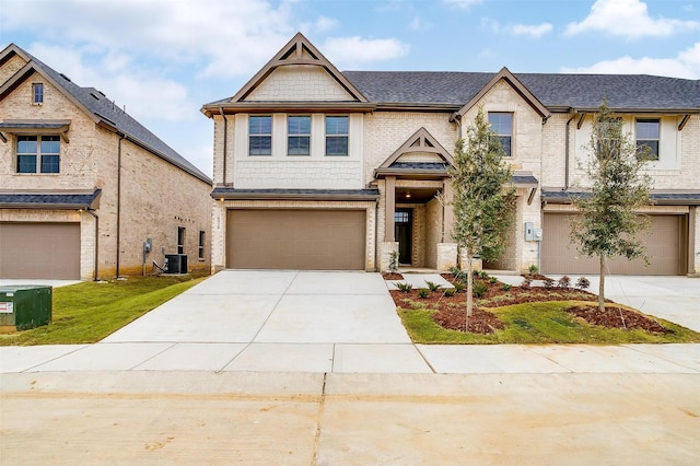 view of front of house featuring driveway, an attached garage, cooling unit, and brick siding