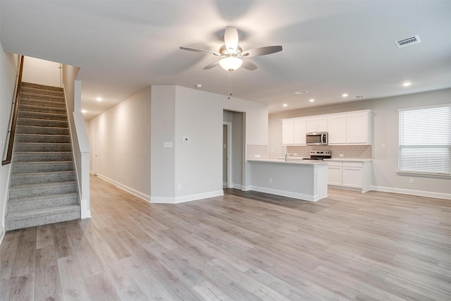 unfurnished living room featuring ceiling fan, a sink, visible vents, stairs, and light wood finished floors