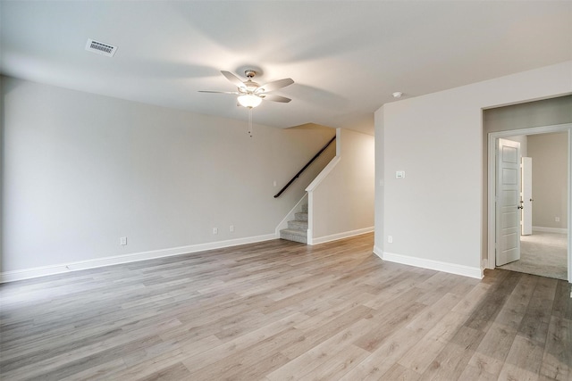 spare room featuring visible vents, stairway, light wood-style floors, ceiling fan, and baseboards