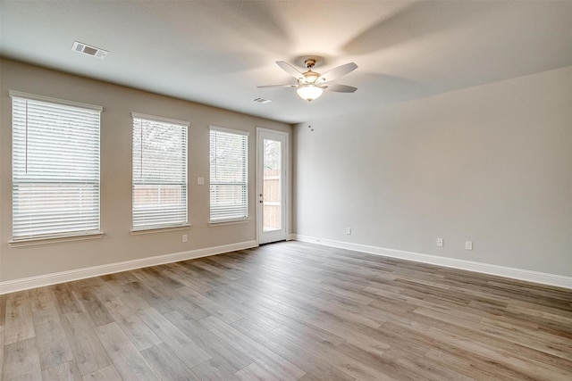 empty room with light wood-style flooring, visible vents, baseboards, and ceiling fan