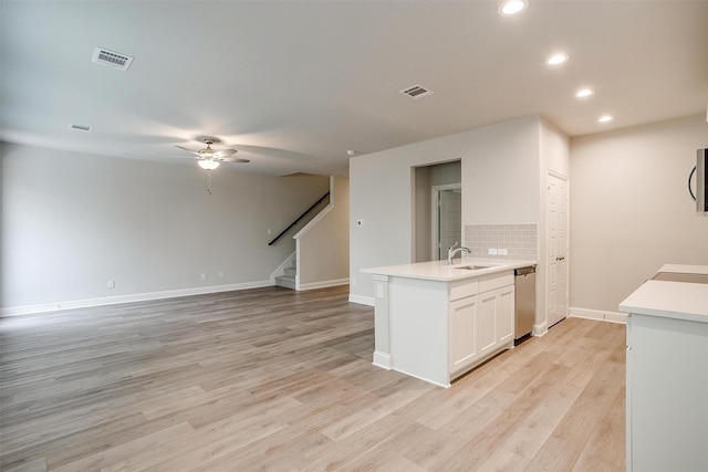 kitchen with tasteful backsplash, visible vents, light wood-style flooring, stainless steel dishwasher, and a sink