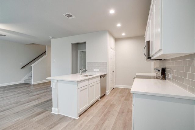 kitchen with a peninsula, visible vents, stainless steel appliances, and white cabinets