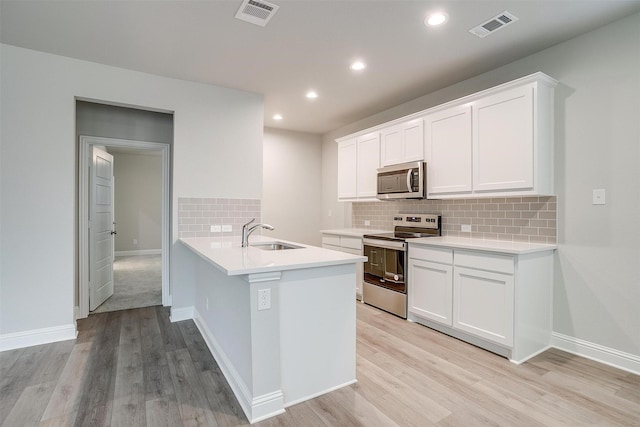 kitchen featuring light countertops, appliances with stainless steel finishes, light wood-style flooring, and visible vents