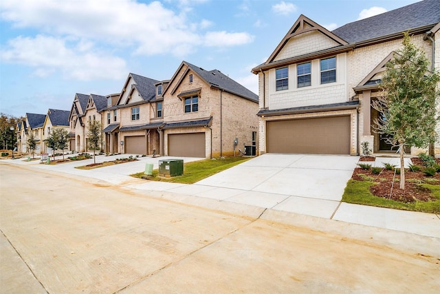 view of front facade featuring an attached garage, a residential view, central AC unit, and concrete driveway