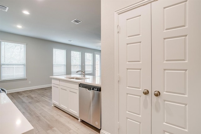 kitchen featuring light countertops, stainless steel dishwasher, a sink, and white cabinetry